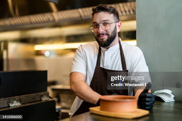 smiling chef leaning on counter standing at restaurant - sud europeo foto e immagini stock