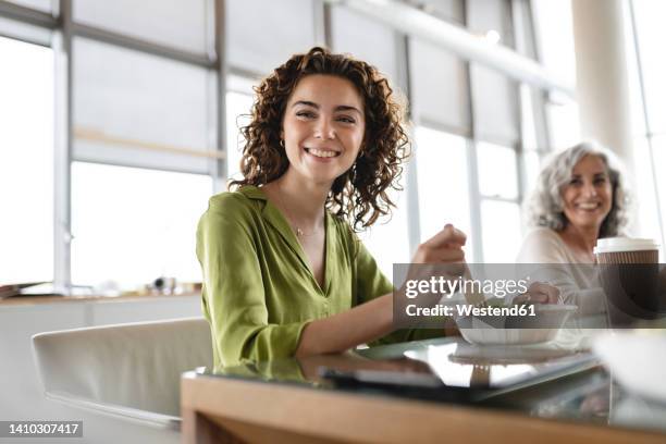 happy young businesswoman with bowl of salad sitting at desk - lunch stock-fotos und bilder