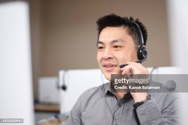 man talking to a customer over headset - call centre asian foto e immagini stock
