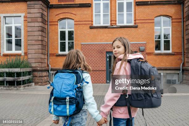 girls girlfriends go to school together holding hands. beginning of the school year. friendship of children with peers - enfant cartable photos et images de collection