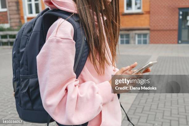 close-up of the hands of a schoolgirl using a mobile phone. teenagers chat, communicate online during recess at school - celular escola imagens e fotografias de stock