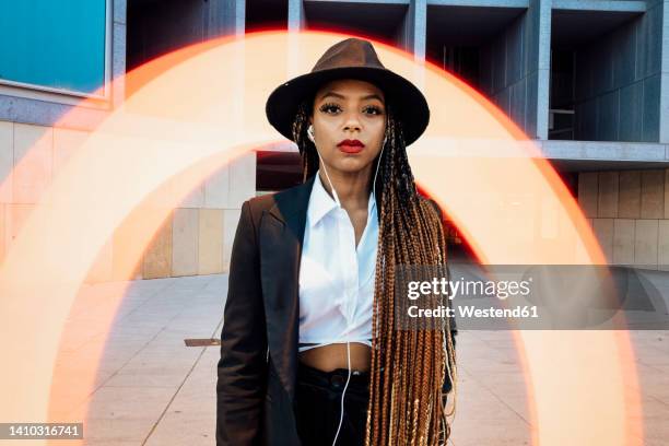 young businesswoman standing in front of orange semi-circle light painting - light painting stockfoto's en -beelden