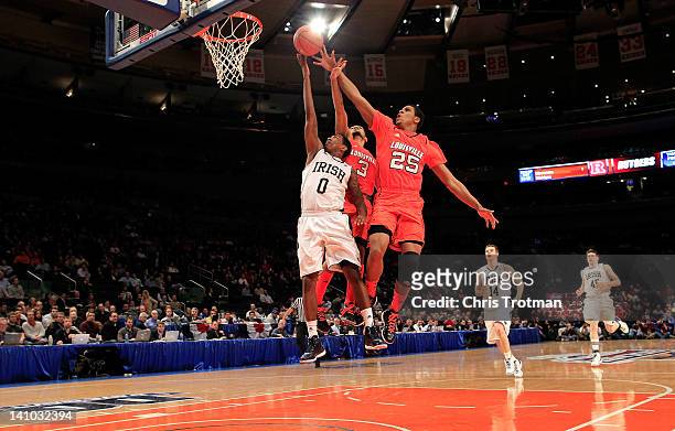 Peyton Siva and Wayne Blackshear of the Louisville Cardinals jump to block the shot of Eric Atkins of the Notre Dame Fighting Irish during the...