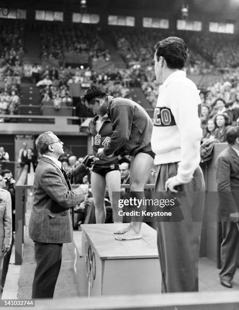 Sammy Lee of the USA receives his gold medal from Olympic committee member H E Fern, after winning the Men's Platform Diving event at the Empire...