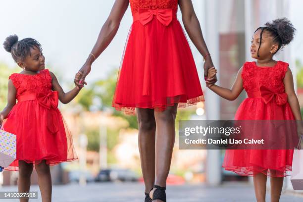 two girls in red dresses look at each other with complicity while shopping - vestido rojo stock-fotos und bilder