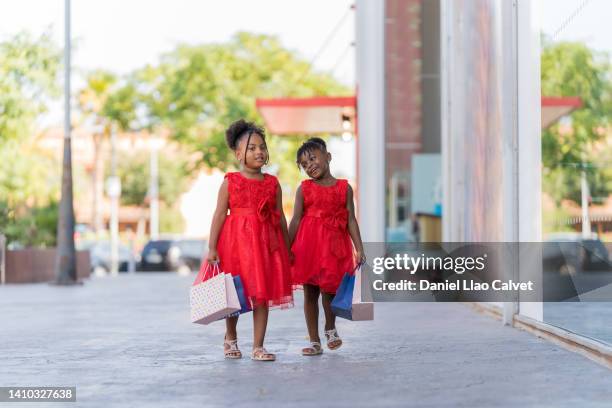 litlle sisters strolling in a shopping mall with shopping bags. - vestido stock pictures, royalty-free photos & images