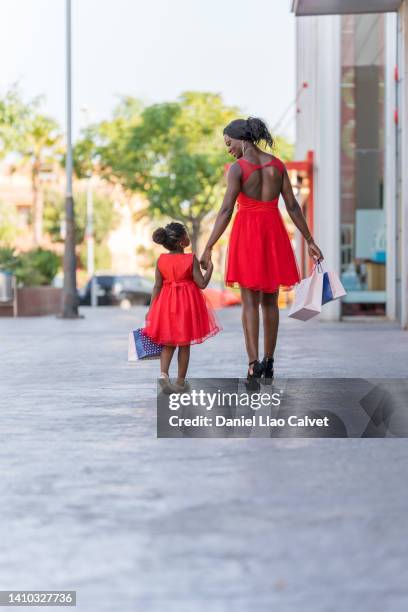 rear view of a mother and daughter shopping at the mall - vestido rojo stock-fotos und bilder