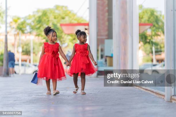 two girls holding hands in shopping centre - vestido ストックフォトと画像