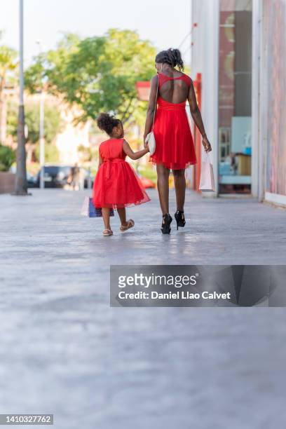 a mother and daughter, dressed in red, go shopping. - vestido rojo stock pictures, royalty-free photos & images