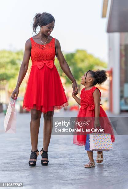 mother and daughter look at each other happily on a shopping day - vestido rojo stock pictures, royalty-free photos & images