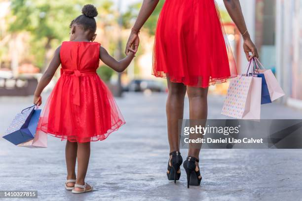 rear view of a unrecognizable mother and daughter shopping at the mall - vestido rojo stock pictures, royalty-free photos & images