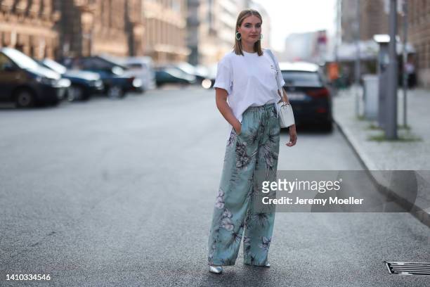 Marie von den Benken is seen wearing a white oversized Riani Shirt, green flower printed wide pants and green earrings and a white leather handbag on...