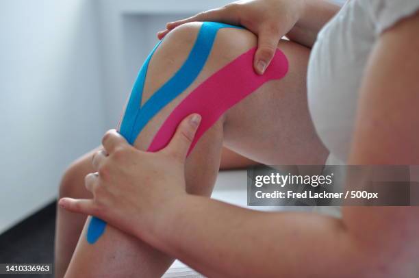 cropped image of spa attendant holding clients knee for massage for pain in salon - kinesiotape stock pictures, royalty-free photos & images