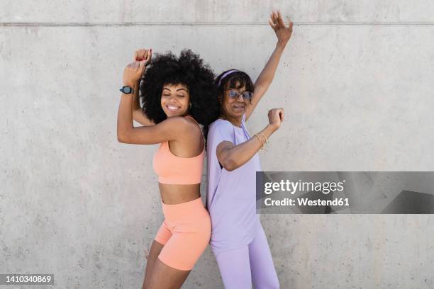 smiling mother and daughter dancing by wall - female dancer stock pictures, royalty-free photos & images