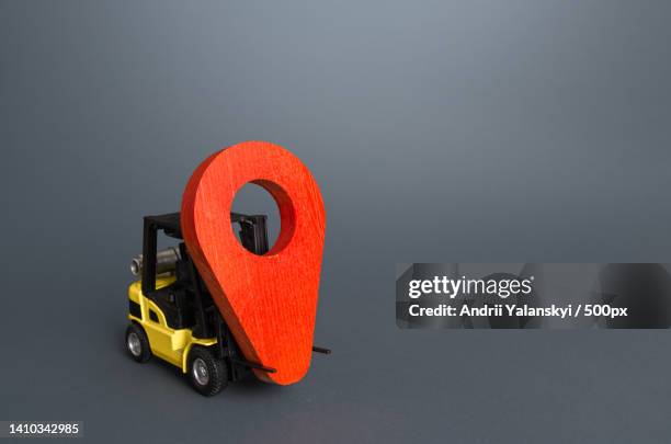 yellow forklift carries a red location pin pointer - real time stock pictures, royalty-free photos & images