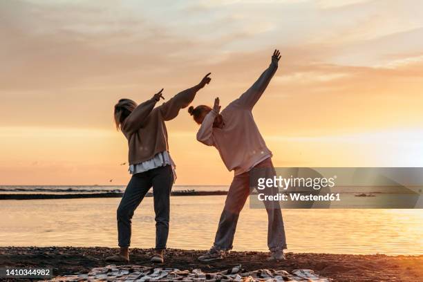 teenage girl with mother doing dab standing at beach - dab dance stock pictures, royalty-free photos & images