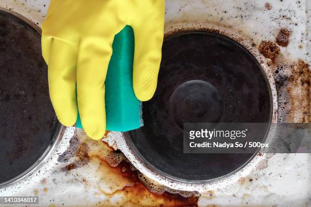 hand in household glove cleaning grease and dirt from kitchen stove - oily slippery stockfoto's en -beelden