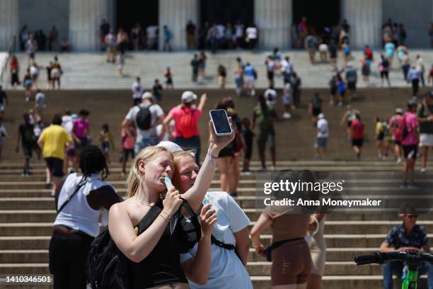 Tourists take selfies of themselves with popsicles during a heatwave in front of the Lincoln Memorial on July 22, 2022 in Washington, DC. According...