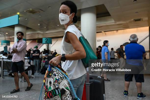 Mask-clad traveler carries her luggage at arrivals hall in Terminal 1 of Humberto Delgado International Airport on July 22, 2022 in Lisbon, Portugal....