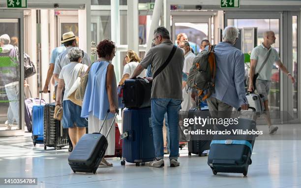 Arriving travelers carry their luggage as they exit Humberto Delgado International Airport on July 22, 2022 in Lisbon, Portugal. The city's airport...