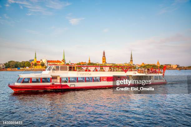 barco turístico sobre los edificios de riga del río daugava. riga, letonia - riga fotografías e imágenes de stock