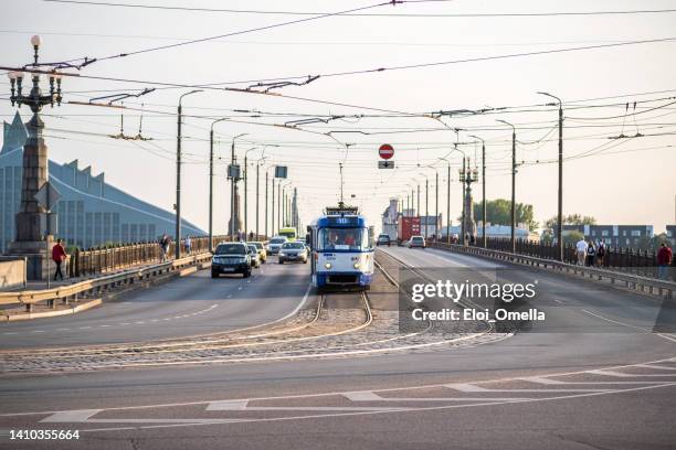 tranvía moderno y coches sobre el puente de akmens en riga, letonia - riga fotografías e imágenes de stock
