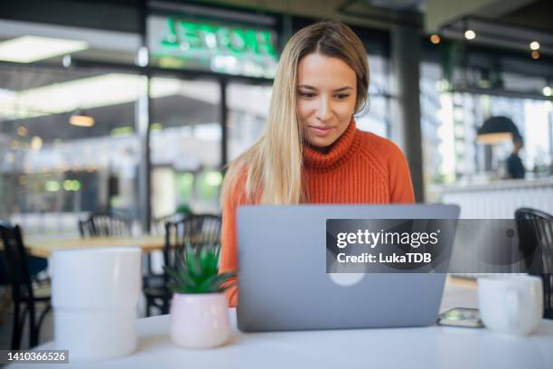 young female at coffee shop using laptop. - switzerland business stock pictures, royalty-free photos & images