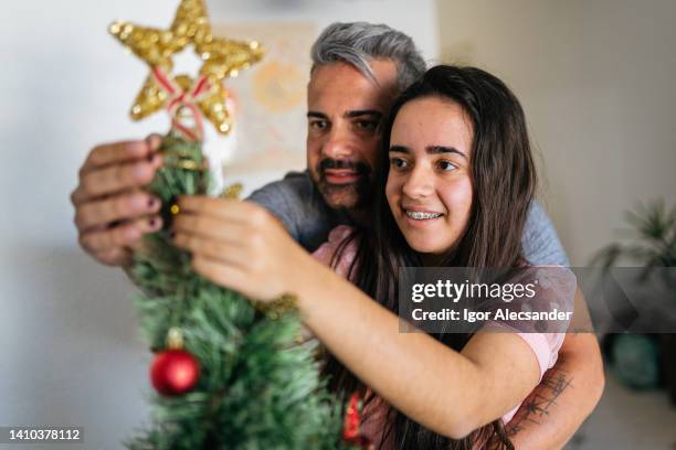 pai e filha juntos decorando a árvore de natal - papa noel - fotografias e filmes do acervo