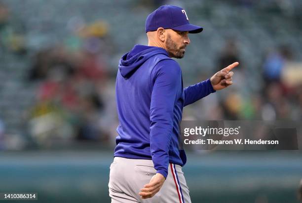 Manager Chris Woodward of the Texas Rangers signals the bullpen to make a pitching change against the Oakland Athletics in the bottom of the fifth...