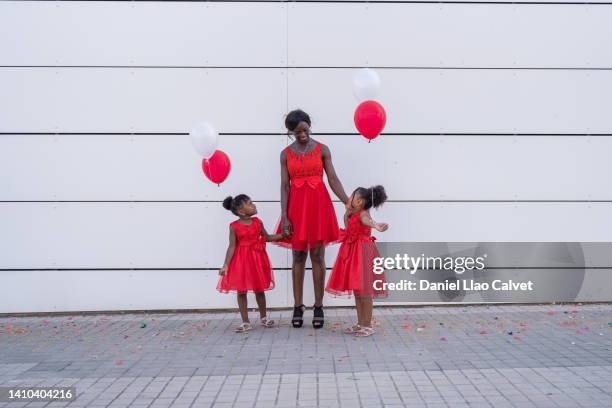 family dressed in red and colorful balloons - vestido rojo stock-fotos und bilder