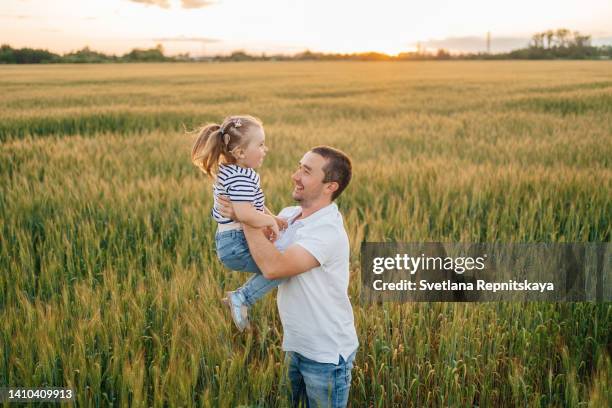 daughter with a cochlear implant in her father's arms in a wheat field - cochlea implant stock pictures, royalty-free photos & images