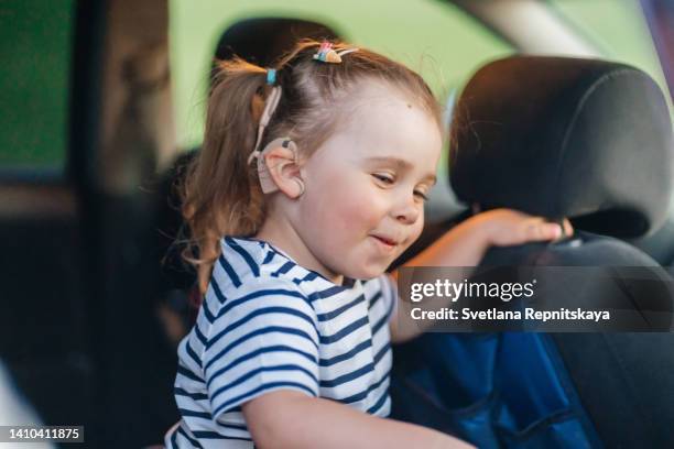 child with a cochlear implant sits in a car seat in a car - cochlea implant stock pictures, royalty-free photos & images