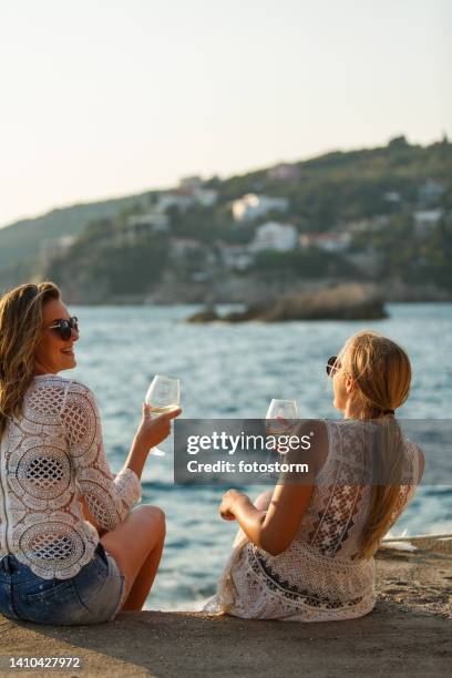 copines appréciant le vin blanc au bord de la mer, se liant, riant et bavardant - vin blanc photos et images de collection