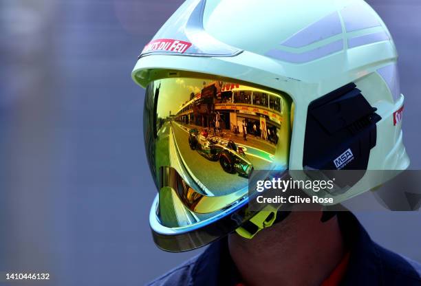 George Russell of Great Britain driving the Mercedes AMG Petronas F1 Team W13 is reflected in the helmet of a track fire marshal during final...
