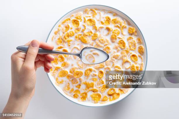 dry cornflakes with honey in a ceramic plate on the dining table at home. flakes with organic farm vegetable soy, almond or animal milk. a woman, a girl or a teenager eats breakfast. the concept of healthy eating, vegetarian and vegan food for breakfast. - corn flakes ストックフォトと画像