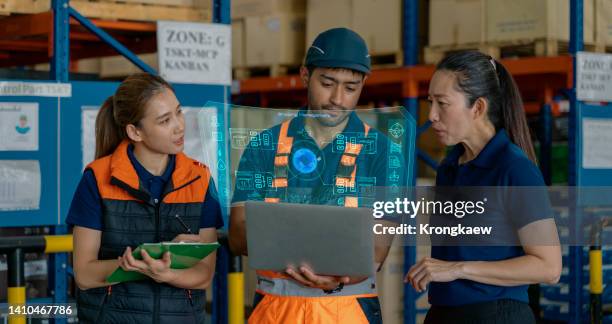 asian warehouse team meeting in the distribution warehouse and discussing the delivery schedule via laptop. virtual screen showing the operation of the transport system. - combat command and control system stock pictures, royalty-free photos & images