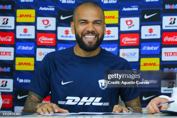 Dani Alves smiles as he signs his contract with the club during his unveiling as new player of Pumas UNAM at La Cantera on July 23, 2022 in Mexico...