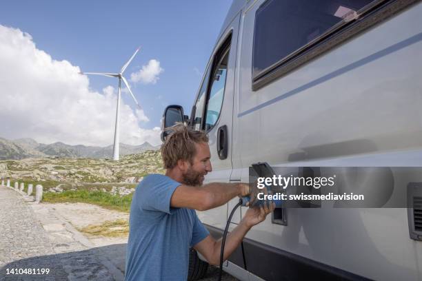 un homme branche un camping-car électrique à recharger - structure actionnée par le vent photos et images de collection