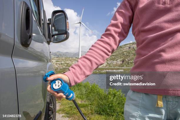 unrecognisable person plugs an electric vehicle for charging - fuel efficiency stock pictures, royalty-free photos & images