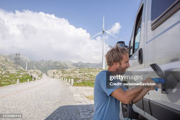 hombre enchufa una autocaravana eléctrica para recargarla - con eficaz consumo de combustible fotografías e imágenes de stock
