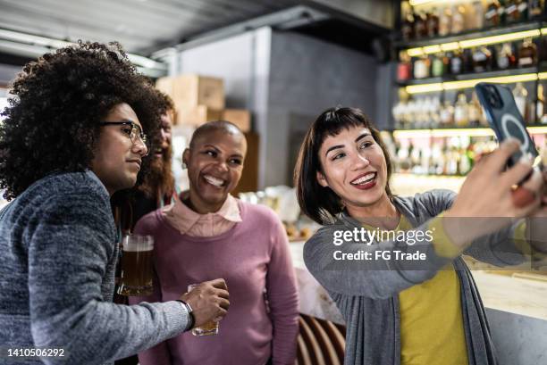 jeune femme prenant des selfies sur le téléphone portable avec des amis au bar - afterwork photos et images de collection