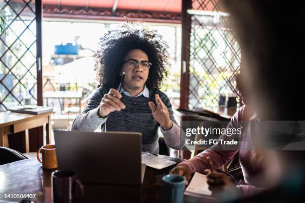 mid adult man talking in a business meeting with coworkers in a restaurant - annoying colleague stock pictures, royalty-free photos & images
