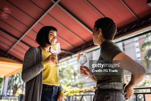 young women talking and drinking at the bar - gin stockfoto's en -beelden