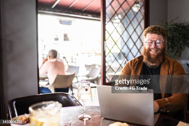 mature man using laptop in a restaurant - virtual lunch stock pictures, royalty-free photos & images