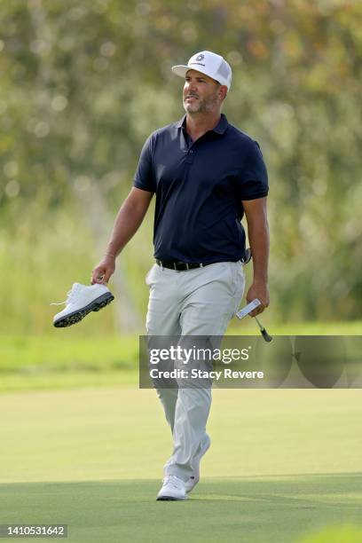 Scott Piercy of the United States walks across the 10th green while holding one of his shoes during the third round of the 3M Open at TPC Twin Cities...