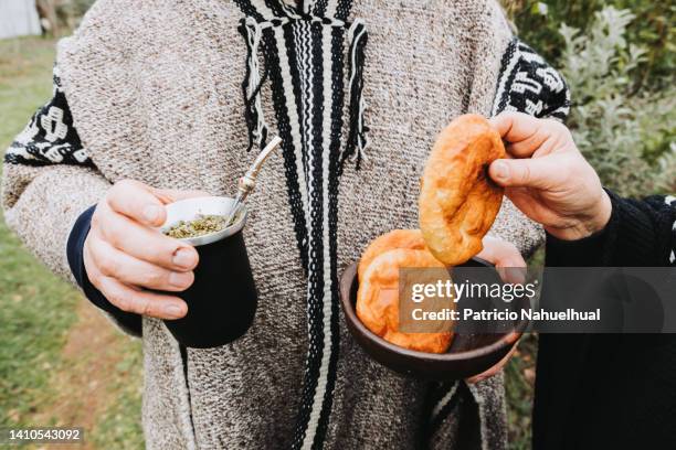 unrecognizable mapuche person using a gray wool poncho, holding a mate and sharing sopaipillas. indigenous culture concept. - indian food bildbanksfoton och bilder