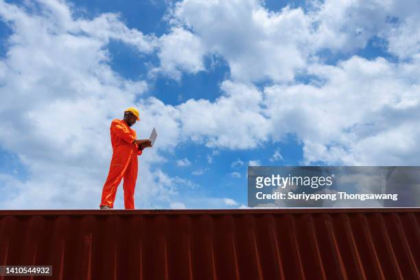 young  man worker control shipping process in container cargo warehouse for business logistics, import export shipping or freight transportation. - global business continuity stock pictures, royalty-free photos & images