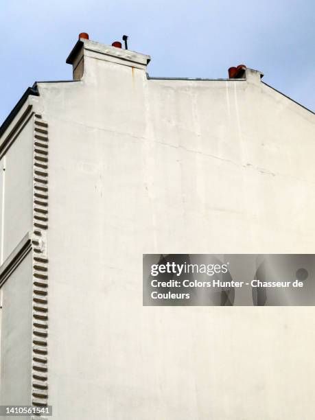 partially and slightly sideways view of the white painted gable with chimney of a house with sky in paris, france - fassade stock-fotos und bilder