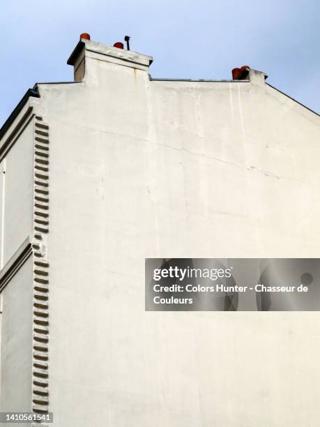 partially and slightly sideways view of the white painted gable with chimney of a house with sky in paris, france - facade fotografías e imágenes de stock