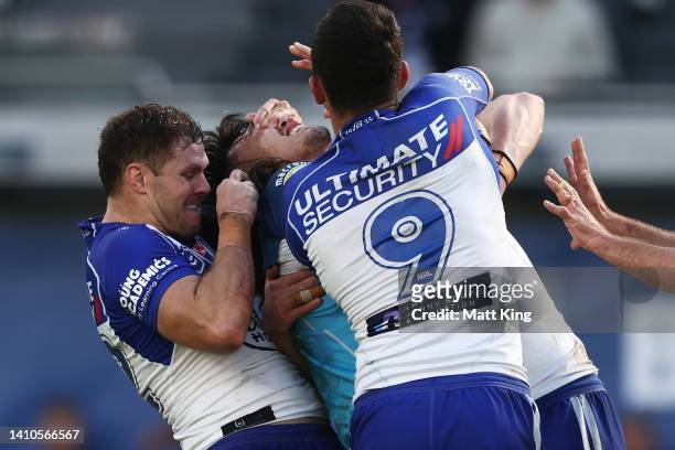 Corey Waddell of the Bulldogs tackles Tino Fa'asuamaleaui of the Titans with his hands on his eyes during the round 19 NRL match between the...